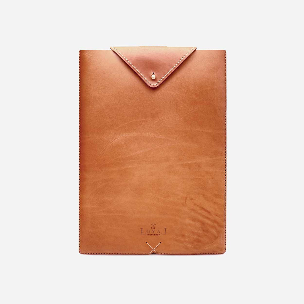 Camel brown leather laptop sleeve with white stitch detailing, brass hardware and an etched logo.