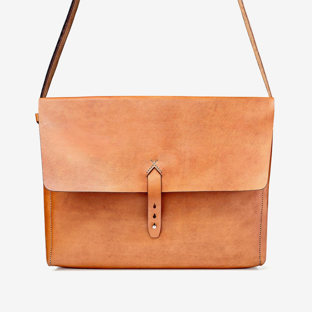 a caramel brown leather messenger style bag with hand stitching and stainless steel hardware detailing