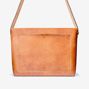 rear view of a caramel brown leather messenger style bag with a thick shoulder strap, hand stitching and large rectangle pocket.