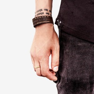 image of persons hand and wrist down by their side wearing a dark brown leather wristband with detail stitching and the word 'hope' etched into it.