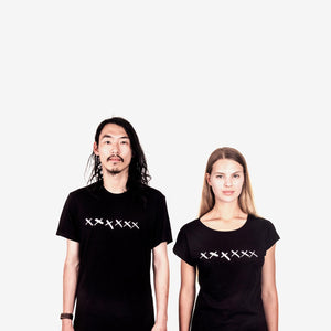 a man and woman standing side by side wearing matching Loyal Workshop black t-shirts with white cross artwork on them.
